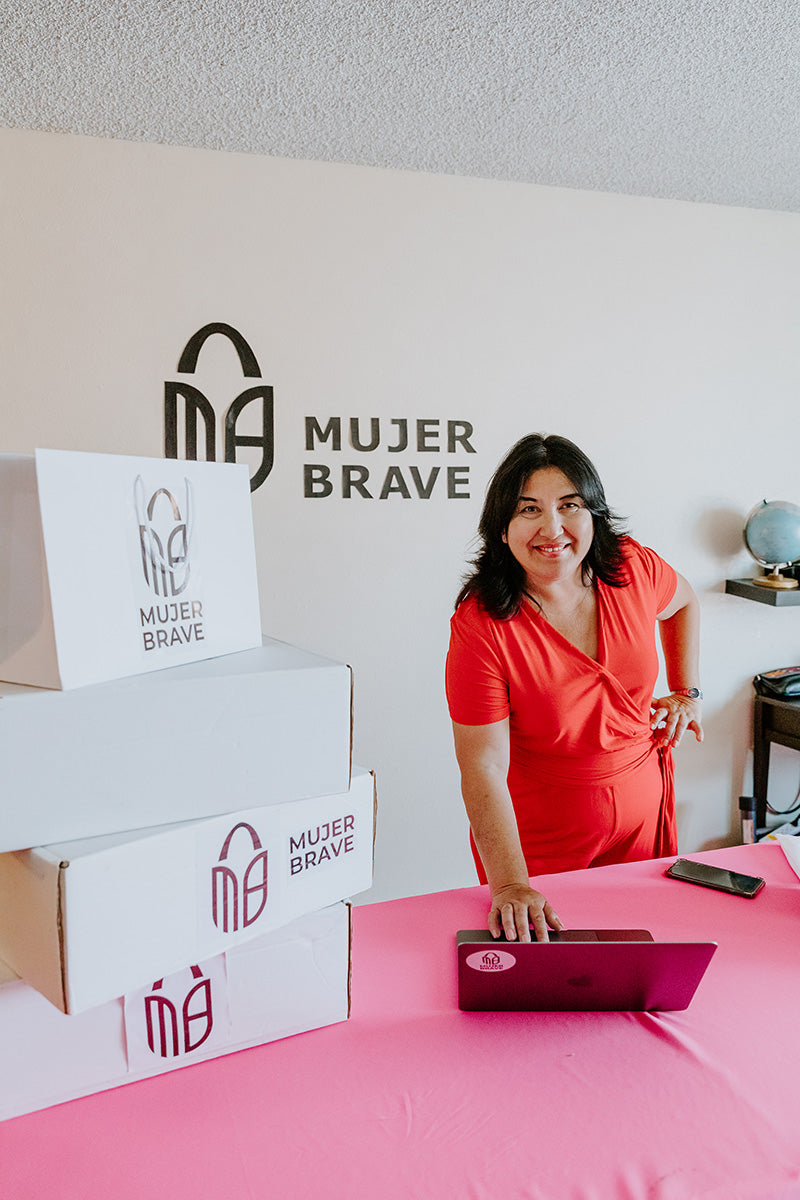 founder of MujerBrave with backdrop of logo display